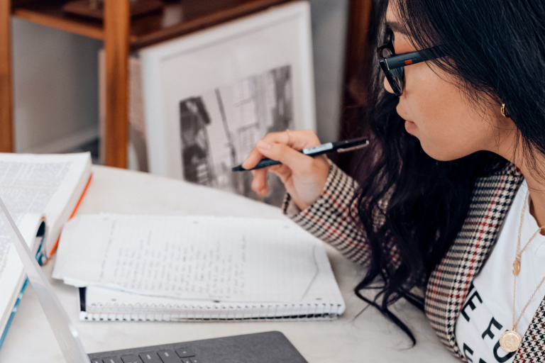 person looking at a computer and writing something down on paper