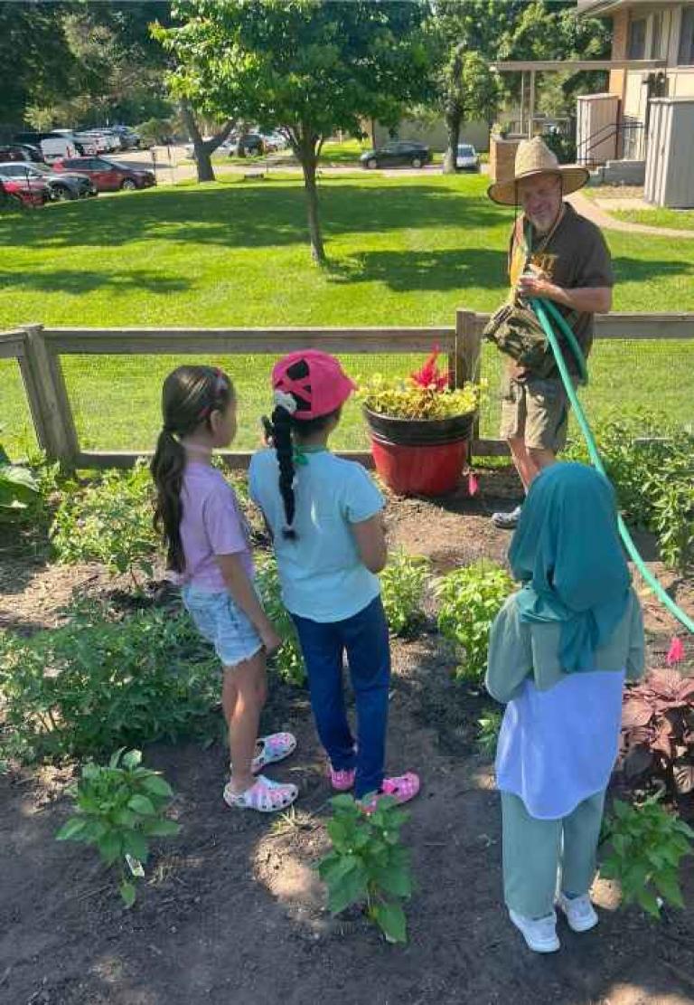 SSW PhD Candidate Kenny Turck instructs youth participants in the DIRT youth program on gardening.