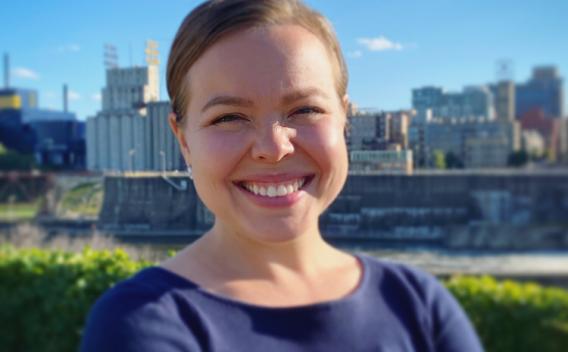 PhD Student Amy R. Dorman outside on a sunny day with the Saint Paul skyline in the background.