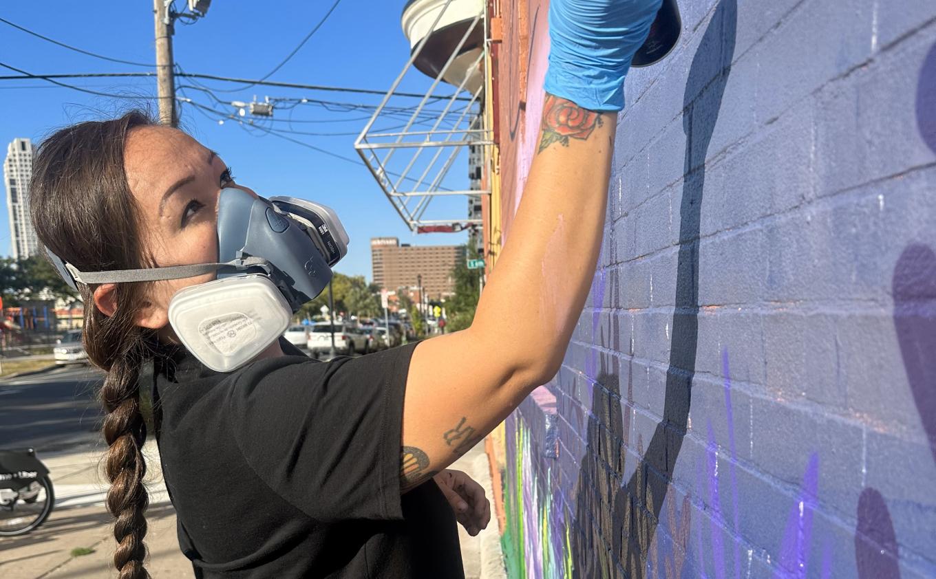 Local Artist Thomasina TopBear works on a mural.