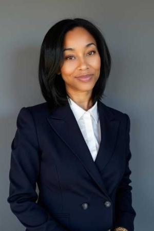 Jessica Coleman, PhD candidate, smiles in a professional portrait. She is wearing a navy blue blazer and a white shirt.