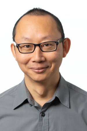 Peter Li, certification and evaluation specialist at the Multidisciplinary Institute for Child Welfare, wears black glasses and a gray button up shirt.