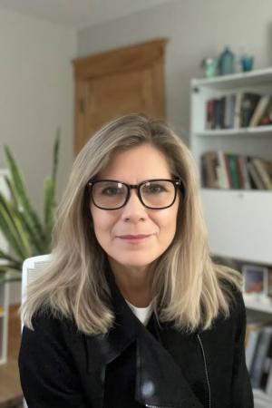 Jessica Toft, PhD wears a black sweater and black glasses in a professional headshot.